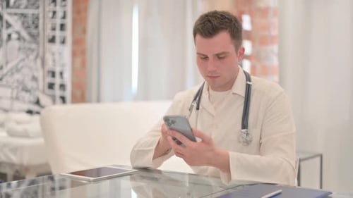 Male Doctor Using Smartphone in Clinic