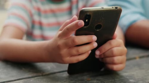 Child Using Smartphone Device at Table