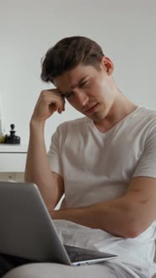 Vertical of Man Feels Tired Listening to Online Lecture Via Laptop