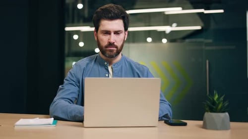 Man Works on Laptop in Modern Office