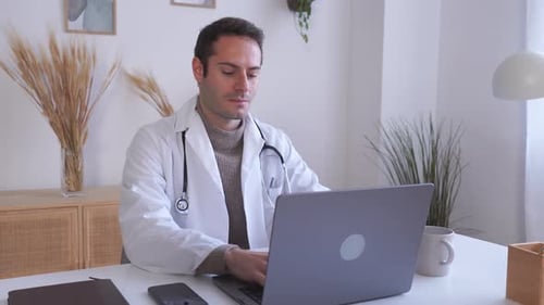 Young Doctor Typing on Laptop in Office