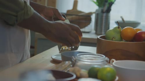 Person Grating Orange in Kitchen for Cooking