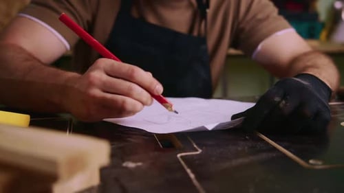 Carpenter Drawing Sketch on Paper in Workshop