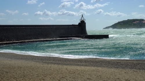 Las fuertes olas rompen alrededor de la muralla del puerto de Collioure, mientras que los fuertes vientos azotan el agua, lo que hace