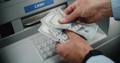 Man Counting US Dollar Bills After Withdrawing Cash Money From ATM Machine