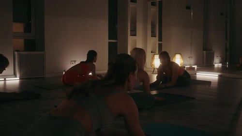 Yoga Class Stretching in Dimly Lit Studio