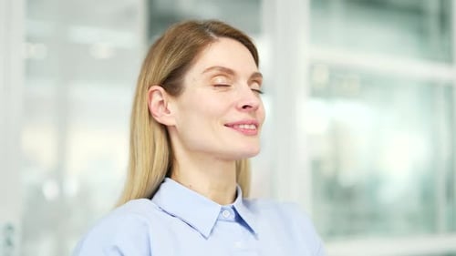 Close up of calm woman relaxing with her eyes closed in a modern office. Portrait of a happy female