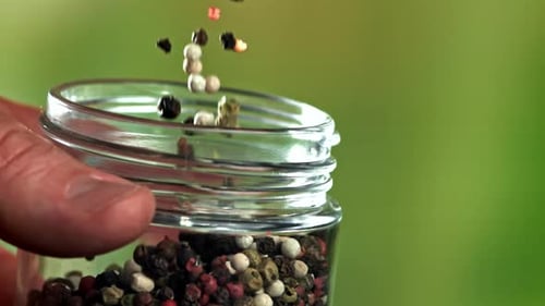 Mixed Peppercorns Pouring Into Glass Spice Jar