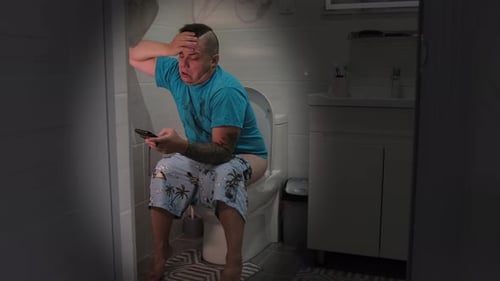 Man Sits on Toilet Using Mobile Phone
