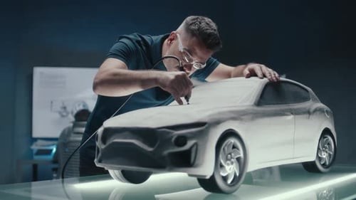 Un concepteur automobile senior travaille sur un prototype de sculpture en argile à l'aide d'un outil rotatif