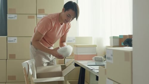 Young Adult Man Packing Box At A Table
