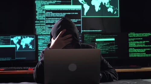 Hacker Working On Laptop With Multiple Monitors