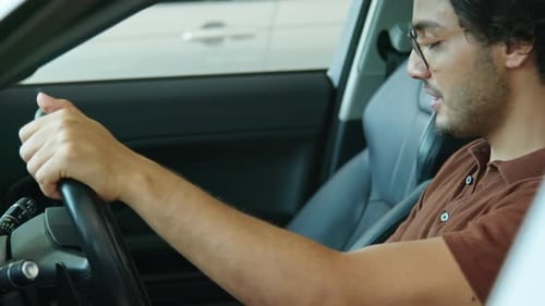Cheerful Man Sitting In New Car In Showroom