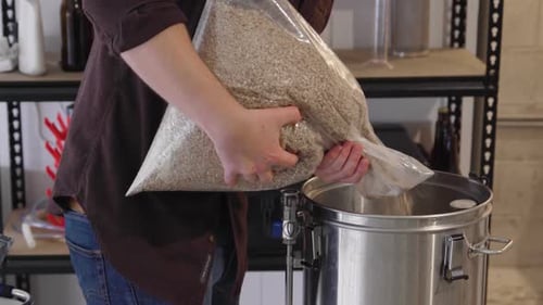 Adicionar grãos de um saco em uma chaleira em uma configuração de cerveja artesanal
