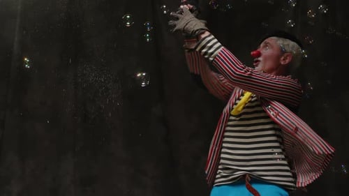 Clown Making Bubbles with Wand in Dark Studio