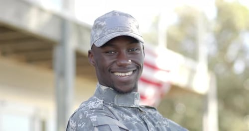 Smiling Soldier in Camouflage Near American Flag