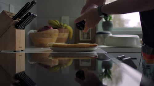 Man Sprinkles Salt over Dish on Kitchen Counter Using Hand Mill