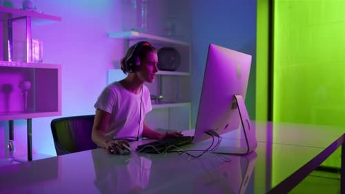 Woman Focused on Computer Gaming in Neon Room