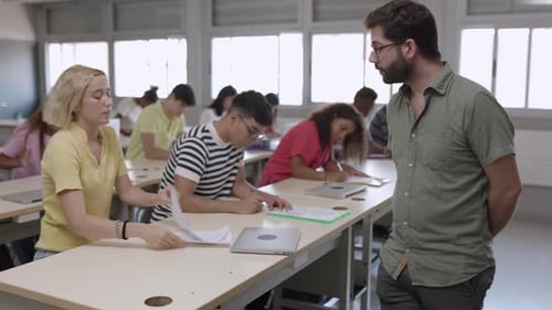 Male Teacher Helping Female Student During High School Exam