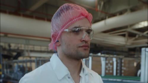 Factory Worker Wearing Hairnet and Safety Glasses in Production Facility