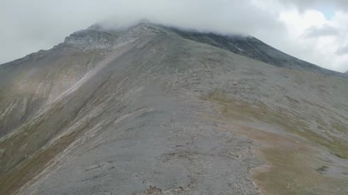 Wolken umarmen einen felsigen Bergrücken
