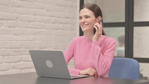 Woman Answering Phone While Working on Laptop