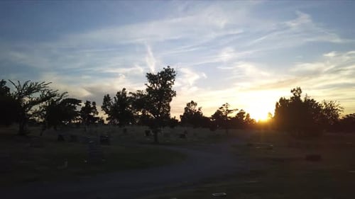 Drone shot of cemetery at dusk. bluish sunset sky. pan right.