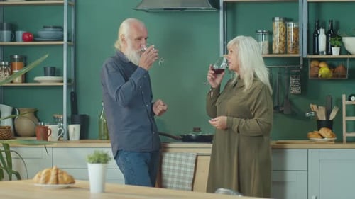 Mature Couple Toasts with Wine in Cozy Kitchen