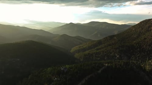 Aerial drone overview of Idaho Springs, Colorado, capturing the sun setting over the mountainous lan