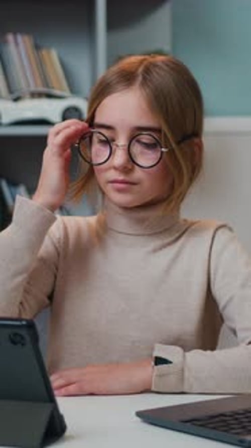 Girl Uses Laptop and Tablet at Desk Indoors
