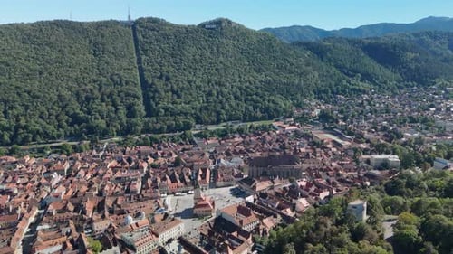 Aerial View of Historic City Nestled Beneath a Steep, Forested Mountain
