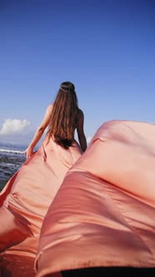 Vídeo vertical de chica con un vestido largo con el océano como telón de fondo en Bali