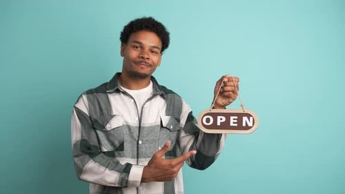 Homme souriant avec panneau ouvert Invitant dans un studio bleu