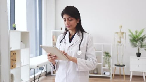 Friendly physician holding digital tablet in hospital room