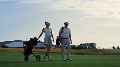 Golfers walking with golf bags on green course