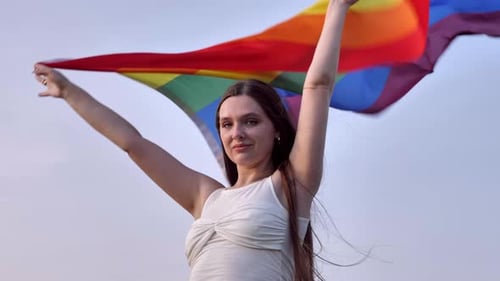 Woman Waves a Pride Flag Against Sky