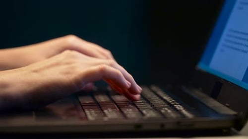 Hands Typing on Laptop Keyboard in Dark Room