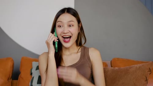 Excited Young Woman Talking on Cell Phone Indoors