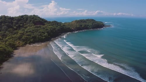 4K UHD aerial drone footage of a perfect empty beach with long waves rolling on the shore at the Pac