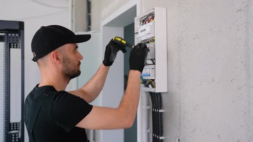 Electrician Works in a Switchboard with an Electrical Connecting Cable
