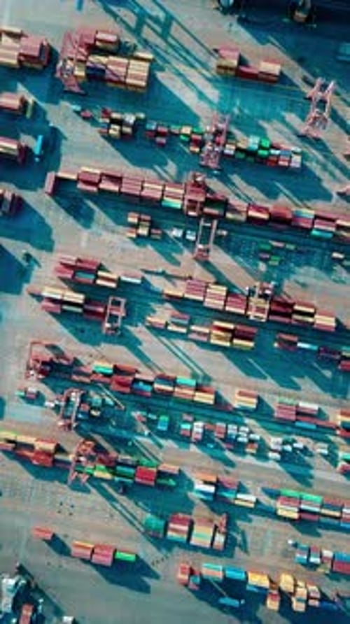 Vertical video of the port - Drone footage of containers, cargo ships and loading cranes in the port
