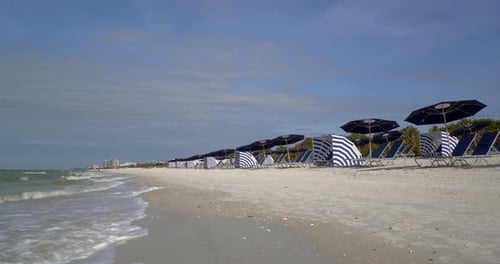 Beach chairs dot the white sand of naples Florida as gentle waves roll ashore