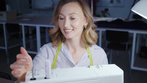 Woman Threads Sewing Machine in Bright Studio