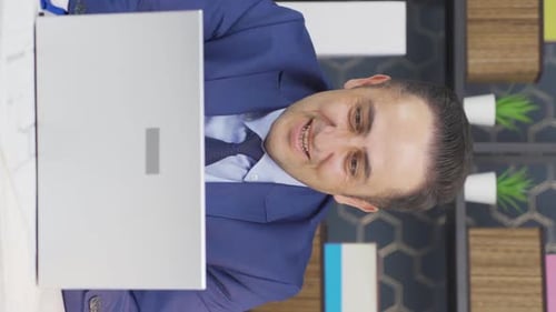 Man Smiles on Laptop Video Call at Desk