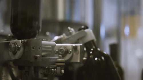 Un bras industriel saisit des bouteilles de vin vides à laver sur la chaîne de montage