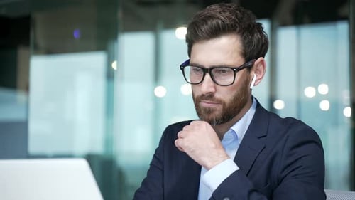 Thoughtful Businessman Working on Laptop in Modern Office