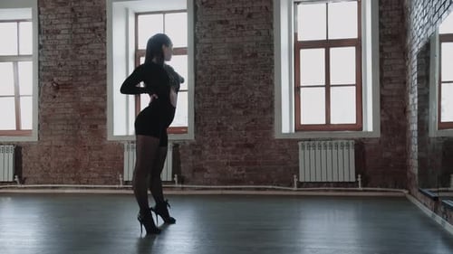 Attractive Woman Dancer in Sexy Black Outfit Practicing in the Studio in Front of a Mirror