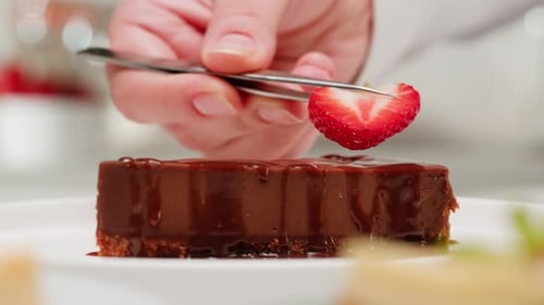 Strawberry Slice Being Placed on Chocolate Cake
