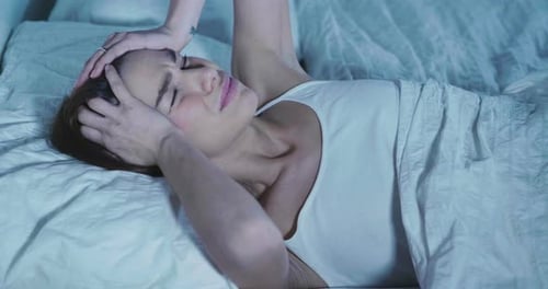 Young Woman Lying in Bed with Headache