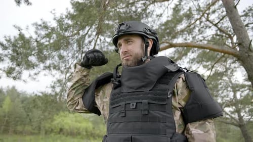 A Ukrainian soldier shows strength in hand, dressed in camouflage and a helmet, looking ahead